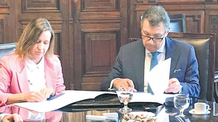El presidente de la CNE Alberto Dalla Vía firmando el convenio junto a Karina Román de AD